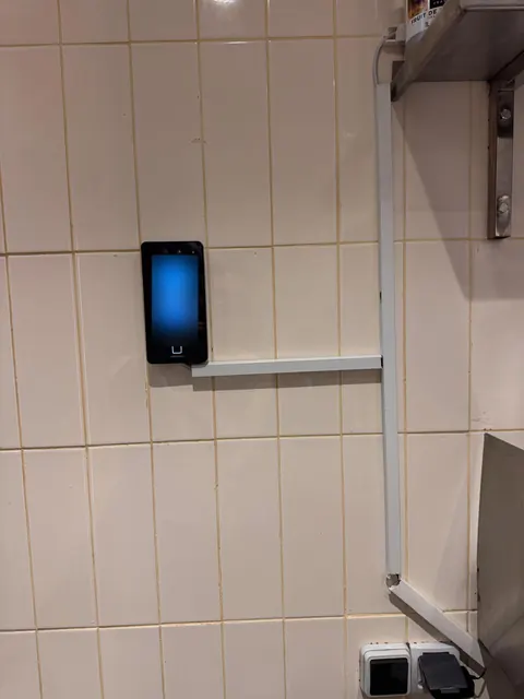 Terminal facial en cuisine, sur un mur carrelé près du poste de préparation.