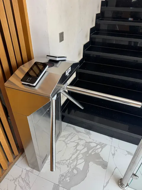 Tourniquet tripode et terminal facial, au pied de l'escalier d'un immeuble.